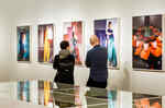 In the exhibition Horst Photographer of Style two people look at photographs hanging on the wall. In the foreground are white vitrines.
