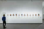 Eine Frau betrachtet mehrere kleine Porträtfotografien von freigesprchenen Todeszelleninsassen in der Ausstellung Martin Schoeller