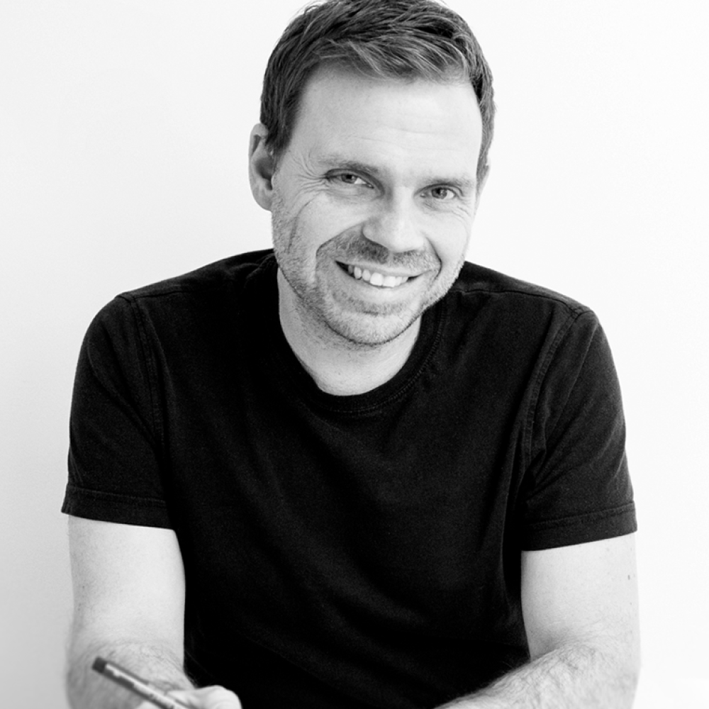 Carsten Heisterkamp an einem Tisch sitzend mit einem Stift in der Hand in Schwarz Weiß