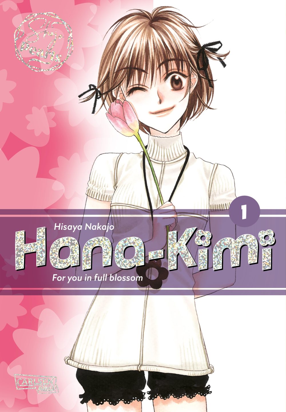 Das Manga-Cover von Hana-Kimi zeigt ein lächelndes Mädchen mit kurzen Haaren, das augenzwinkernd eine Blume hält, vor einem rosa Hintergrund.