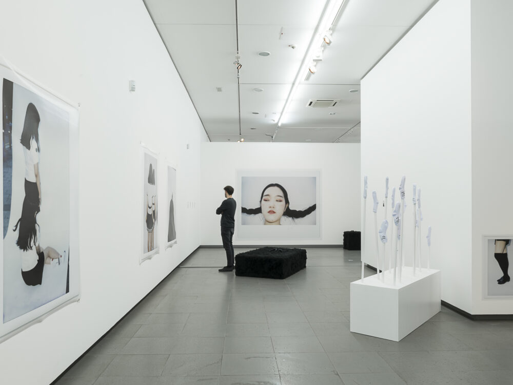 A person looks at photographs hanging on the wall in the exhibition gute Aussichten at the NRW Forum