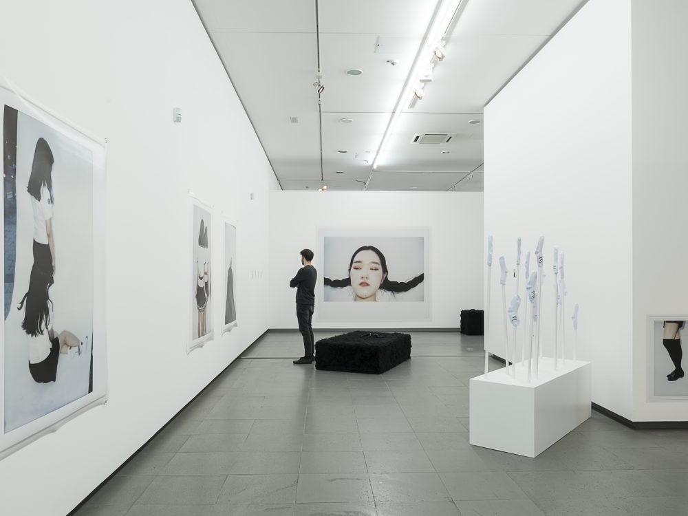 A person looks at photographs hanging on the wall in the exhibition gute Aussichten at the NRW Forum
