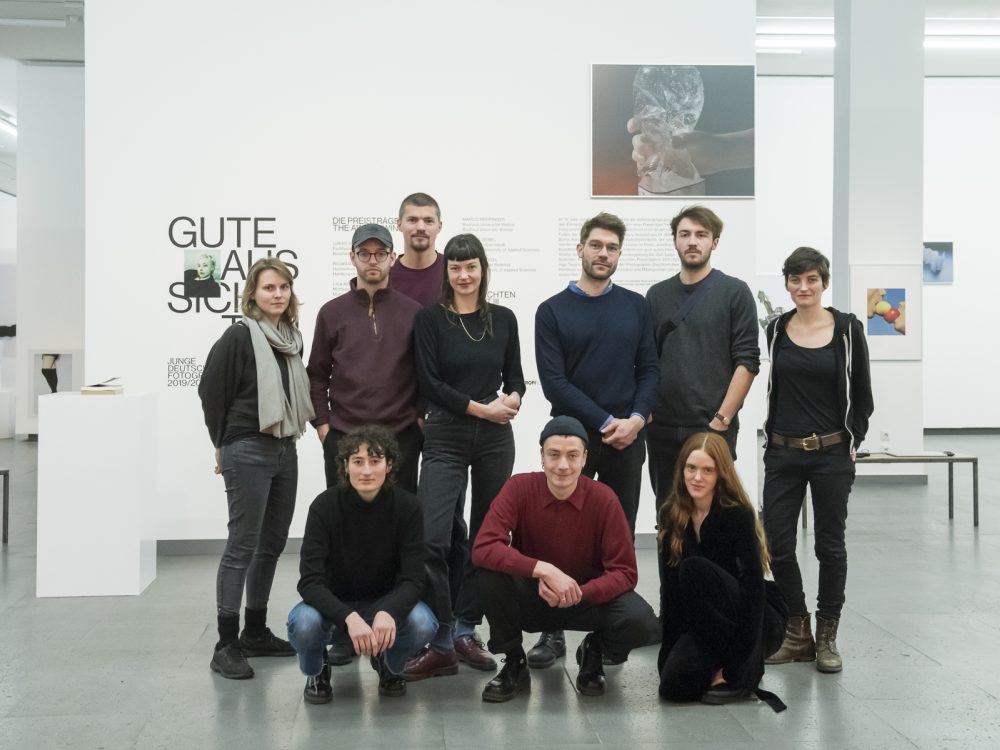 The artists of the exhibition gute Aussichten are posing for a group photo in the exhibition space.