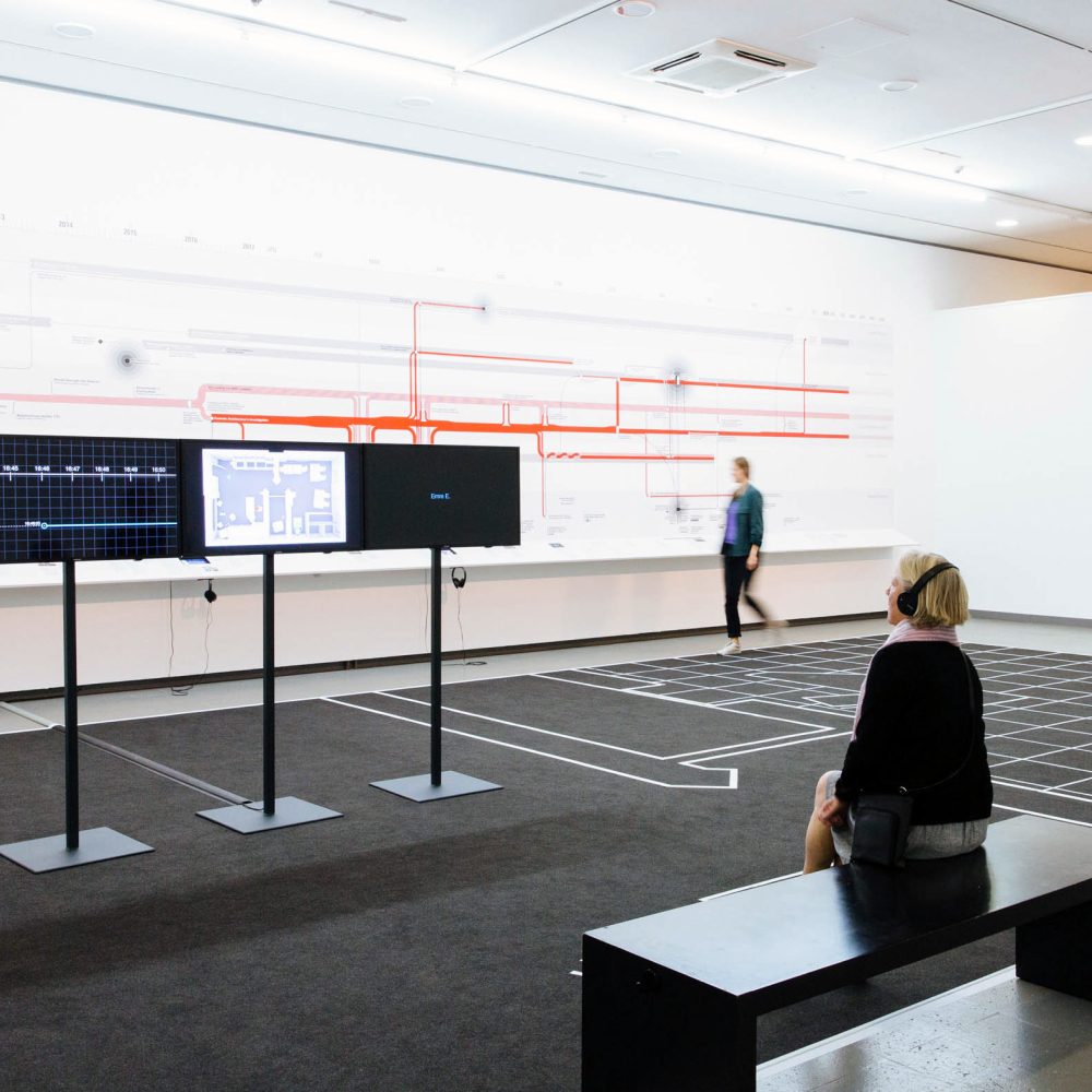 Mehrere Personen betrachten ein Kunstwerk von Forensic Architecture in der Ausstellung Im Zweifel für den Zweifel