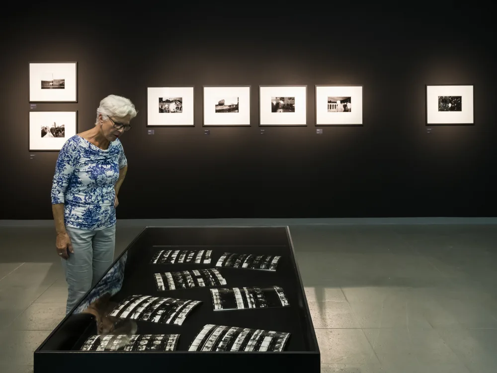 A woman looks into a showcase at the Martin Parr retrospective