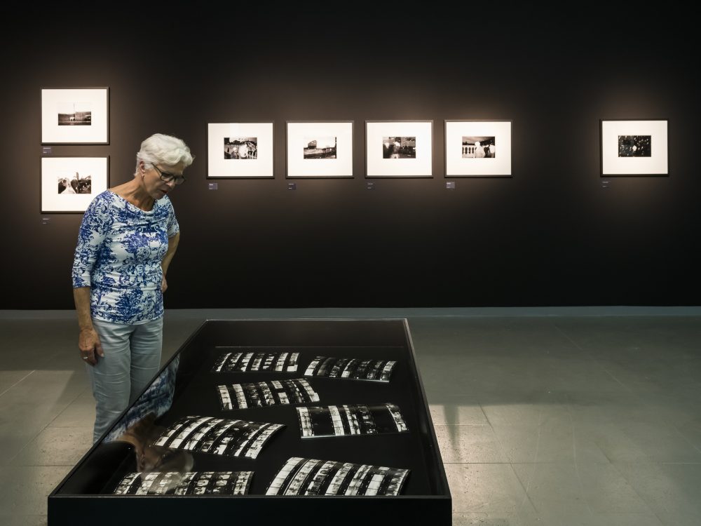 A woman looks into a showcase at the Martin Parr retrospective