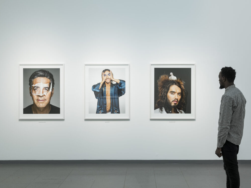 Ausstellungsansicht mit einem Mann, der drei Porträts aus der Serie Portraits in der Ausstellung Martin Schoeller betrachtet