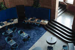 Gastronomie Pong mit mehreren blauen, mit Blumen dekorierten Tischen und blauen Stühlen auf einem blauen Teppich vor roten Backsteinwand