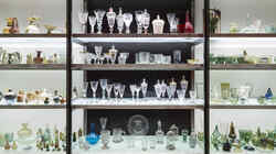 Regal mit Glasböden in dem viele bunte Gläser und Glasartefakte stehen