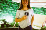 Eine junge Frau hält ein Abzeichen der Akademie der Avantgarde hoch und lächelt dabei