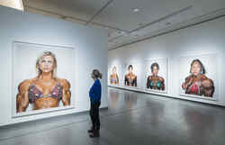 Eine Frau betrachtet Fotos von weiblichen Bodybuilderinnen in der Ausstellung Martin Schoeller