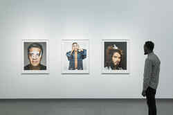 Ausstellungsansicht mit einem Mann, der drei Porträts aus der Serie Portraits in der Ausstellung Martin Schoeller betrachtet