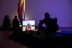 Drei Personen sitzen in einem dunklen Raum vor hell erleuchten Monitoren