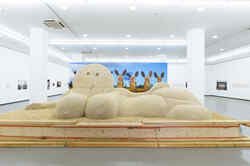 Ausstellungsansicht der Ausstellung Olaf Breuning mit einer großen, liegenden Skulptur aus Sand