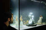 A man presses his nose against the glass pane of an aquarium in which there are small sculptures and fish in the water