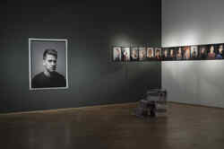 Several portrait photos hang on a black and a white wall in the NRW Forum