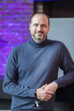 Hüftporträt von Alain Bieber, dem künstlerischen Leiter des NRW Forums, mit blaugrauem Rollkragenpullover