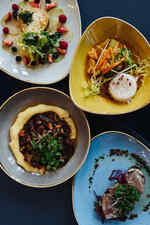 Vier bunte Teller mit verschiedenen, dekorativ angerichteten Gerichten