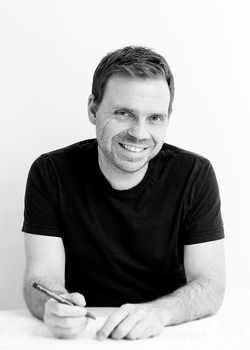 Carsten Heisterkamp an einem Tisch sitzend mit einem Stift in der Hand in Schwarz Weiß