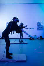 Zwei Personen spielen in einem blau beleuchteten Raum mit VR Brillen auf dem Kopf und Controllern in der Hand